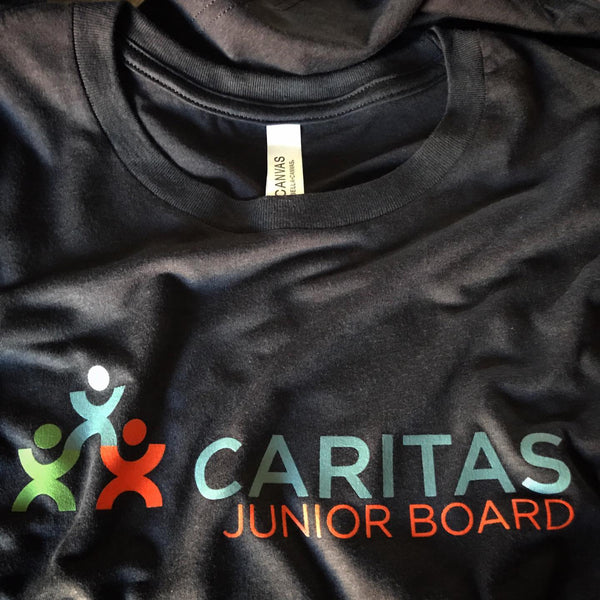 Caritas Junior Board logo in full color on a black tee, laid flat at RVA Threads screen printing, Virginia