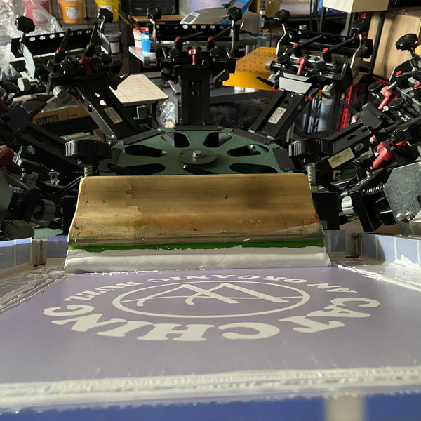Catching An Organic Buzz screen with white ink and the squeegee on the press at RVA Threads screen printing, Virginia