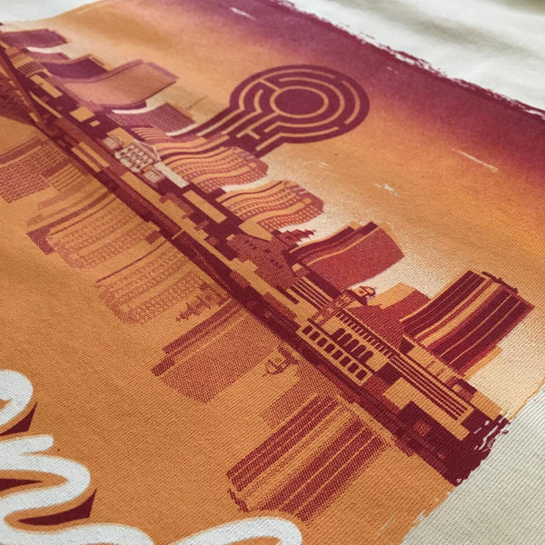 City skyline print in orange and red ink on natural fabric, close up at RVA Threads screen printing, Virginia