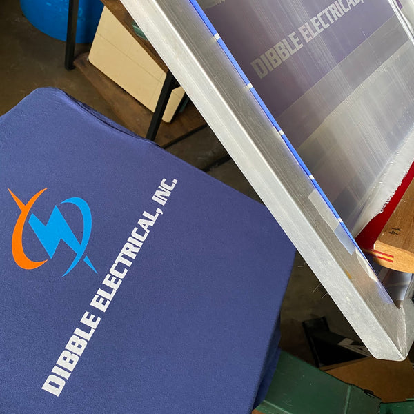 Dibble Electrical, Inc. logo on a violet tee with the screen raised on the press at RVA Threads screen printing, Virginia