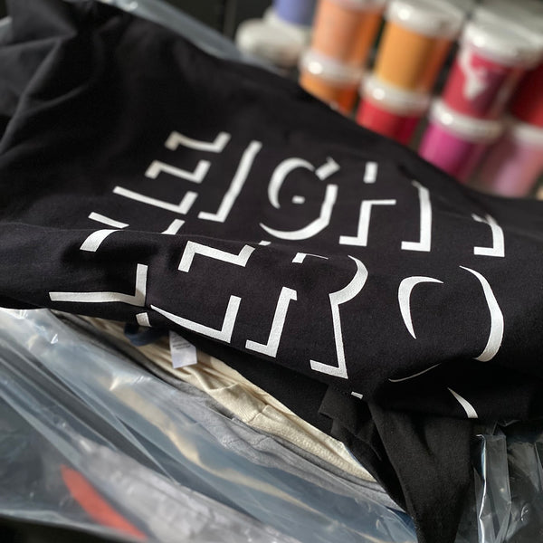 Eight Zero lettering in white ink on black tees, still in the bag at RVA Threads screen printing, Virginia