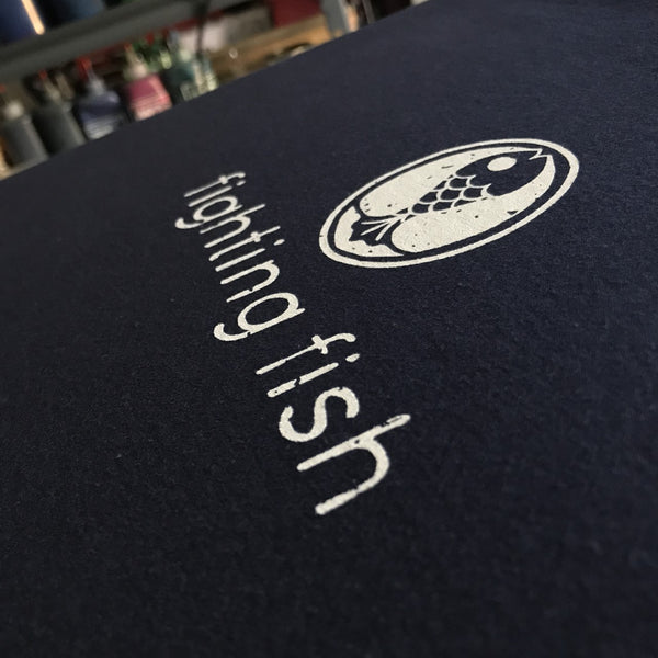 Fighting Fish logo in white ink on a navy tee, close up of the print at RVA Threads screen printing, Virginia