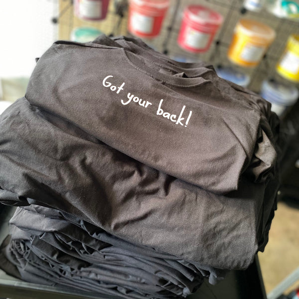 Got Your Back script in white ink on charcoal shirts, folded and stacked after printing at RVA Threads screen printing, Virginia