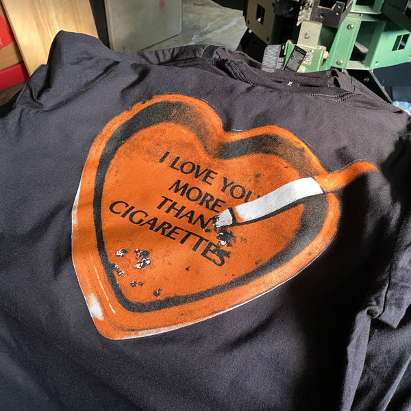 I Love You More Than Cigarettes heart design in orange ink on a black tee at RVA Threads screen printing, Virginia