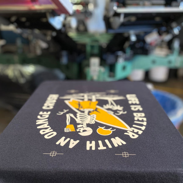 Life Is Better With An Orange Crush design in white and orange ink on a navy tee on the press at RVA Threads screen printing, Virginia