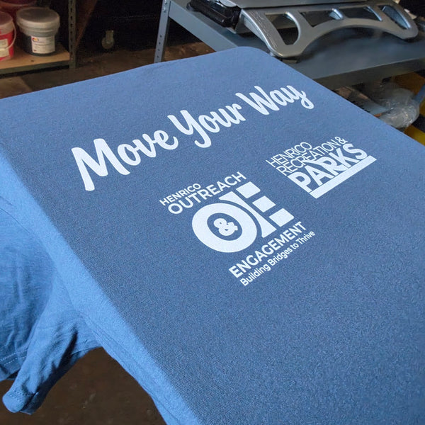 Move Your Way tee with Henrico Parks and Outreach & Engagement logos in white ink on blue, on the press at RVA Threads screen printing, Virginia