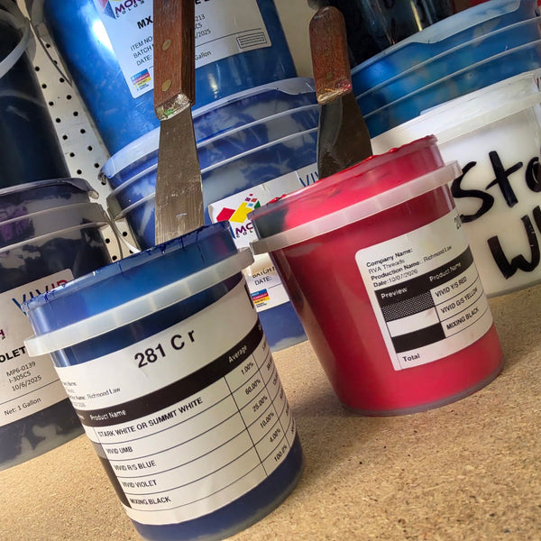 Freshly mixed buckets of 281 C navy and red plastisol ink with palette knives, beside violet and white inks at RVA Threads screen printing, Virginia