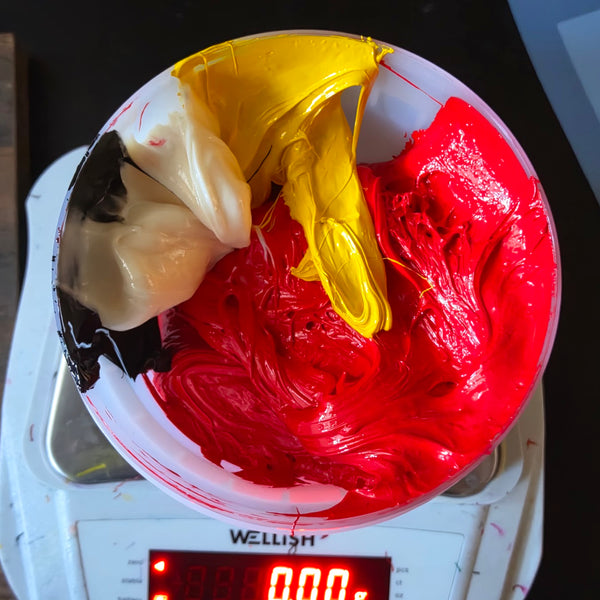 Cup of red, yellow, white and black ink on a digital scale while mixing a custom color at RVA Threads screen printing, Virginia