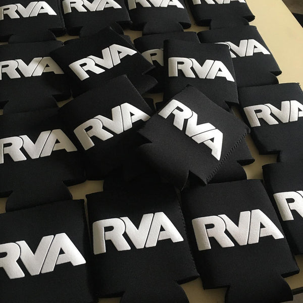 RVA lettering in white ink on black can koozies piled after printing at RVA Threads screen printing, Virginia