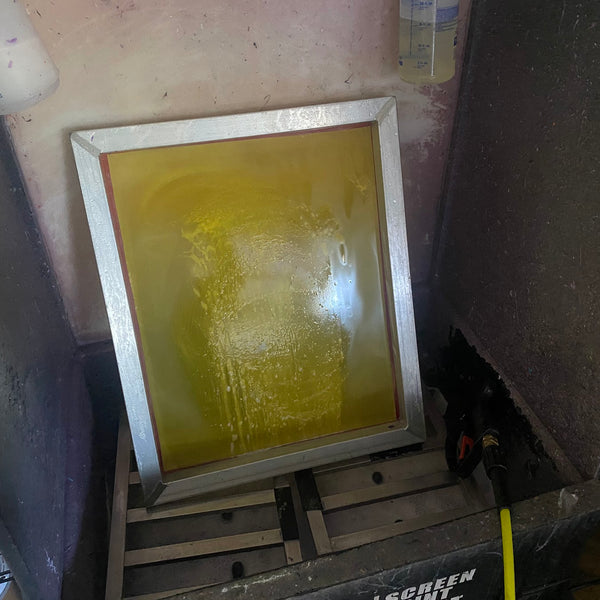 Screen freshly coated with yellow emulsion drying in the screen cabinet at RVA Threads screen printing, Virginia