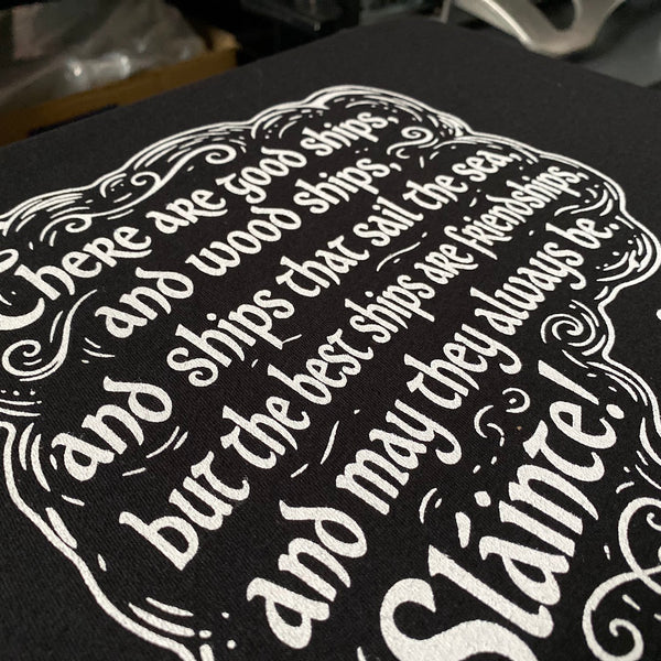 Slainte toast design in white ink on a black tee, close up of the lettering at RVA Threads screen printing, Virginia