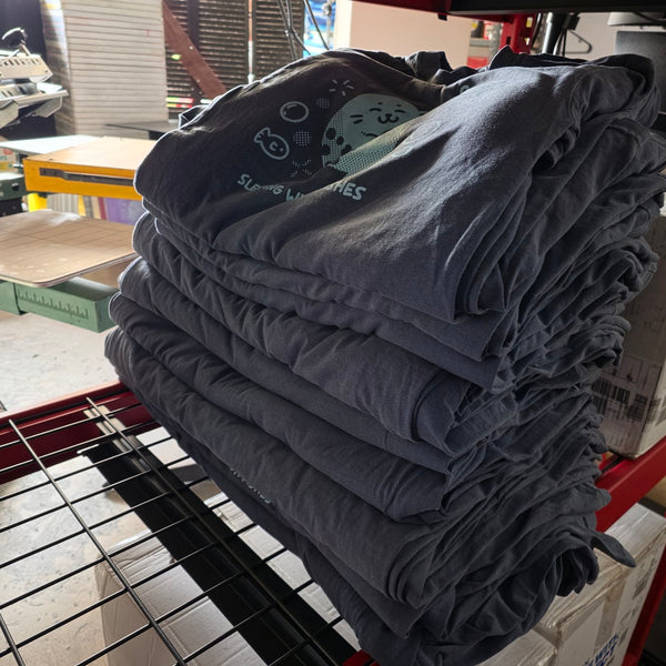 Sleeping With Da Fishes seal tees in light blue on Denim Comfort Colors 1717, folded and stacked at RVA Threads screen printing, Virginia