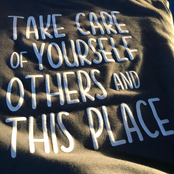Take Care Of Yourself, Others And This Place lettering in white ink on a charcoal tee at RVA Threads screen printing, Virginia