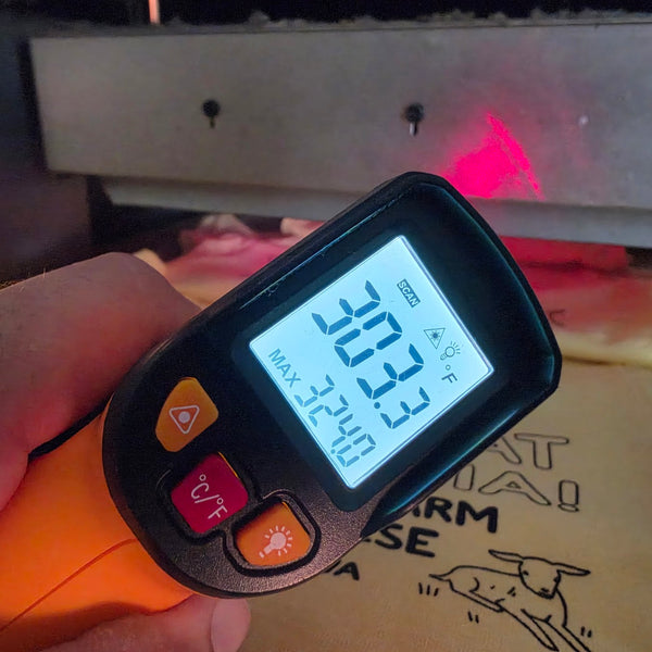 Infrared thermometer reading 303 degrees on a yellow Goat-Topia shirt at the conveyor dryer at RVA Threads screen printing, Virginia