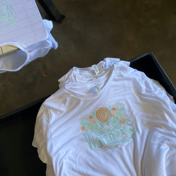 Printed white tees with a mint and peach floral design stacked in a tray at RVA Threads screen printing, Virginia