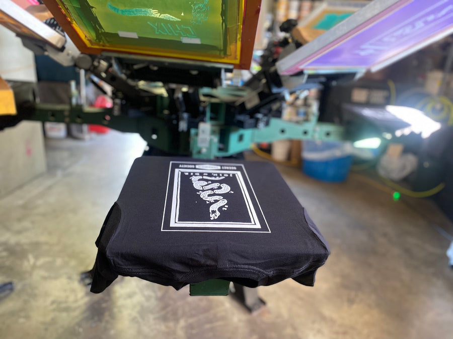 Black shirt printing on a six-color press at RVA Threads screen printing, Virginia