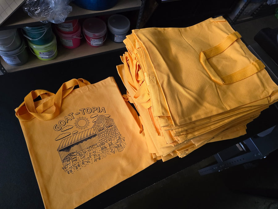 Stack of Goat-Topia gold tote bags printed in black ink at RVA Threads screen printing, Virginia