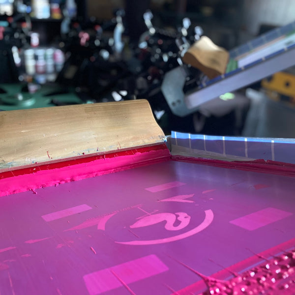 Pink ink on a screen during a print run at RVA Threads screen printing, Virginia