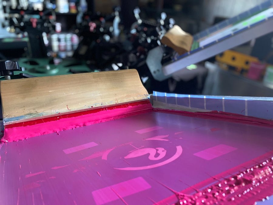 Pink ink on a screen during a print run at RVA Threads screen printing, Virginia