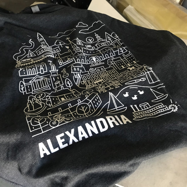 Alexandria city illustration in white and gold ink on a heather navy tee, laid flat at RVA Threads screen printing, Virginia
