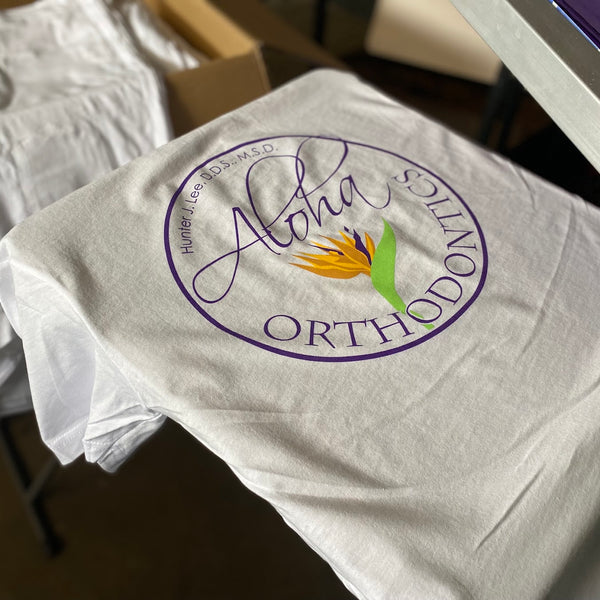 Aloha Orthodontics logo in purple and orange ink on a white tee at RVA Threads screen printing, Virginia