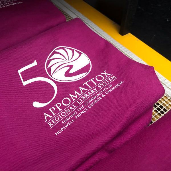 Appomattox Regional Library System 50th anniversary logo in white ink on a berry tee at RVA Threads screen printing, Virginia