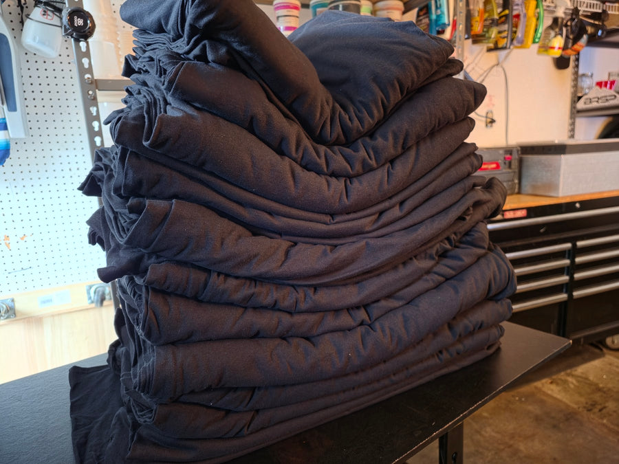 Tall stack of folded black t-shirts squared up on the work table at RVA Threads screen printing, Virginia