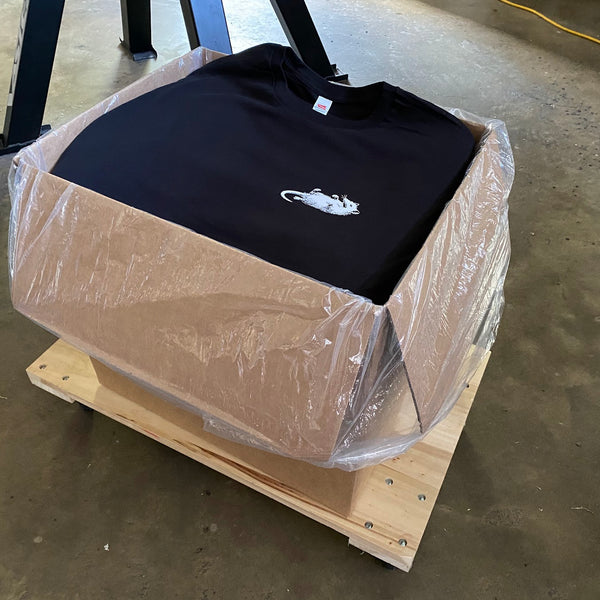 Printed black tees packed in a plastic lined box on a pallet for delivery at RVA Threads screen printing, Virginia