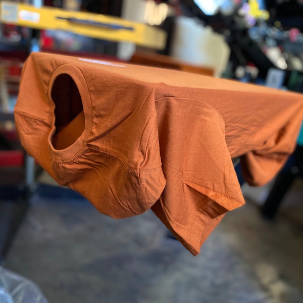 Blank orange tee draped over the press pallet, ready to print at RVA Threads screen printing, Virginia