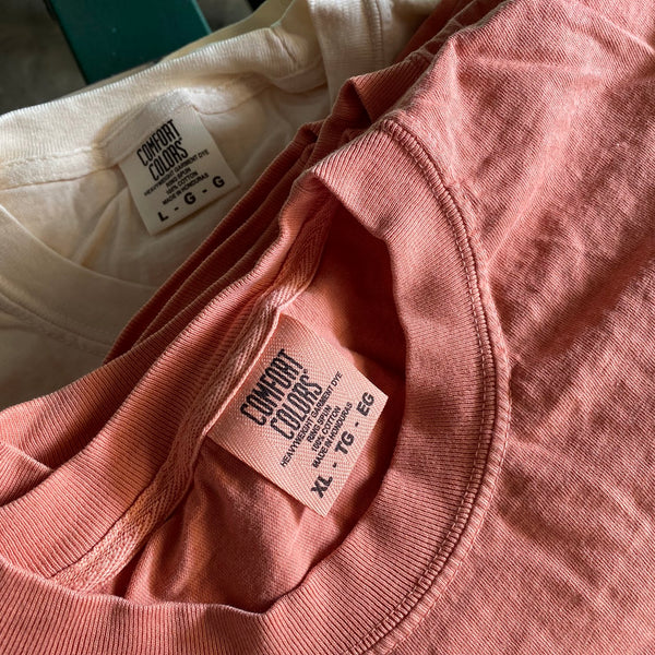 Blank peach and ivory Comfort Colors tees side by side with the collar tags showing at RVA Threads screen printing, Virginia