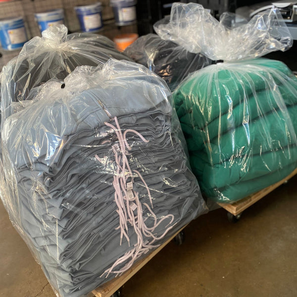 Printed charcoal and green tees bagged in plastic and ready for delivery at RVA Threads screen printing, Virginia