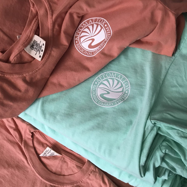 Circular shell logo in white ink on terracotta and mint tees at RVA Threads screen printing, Virginia