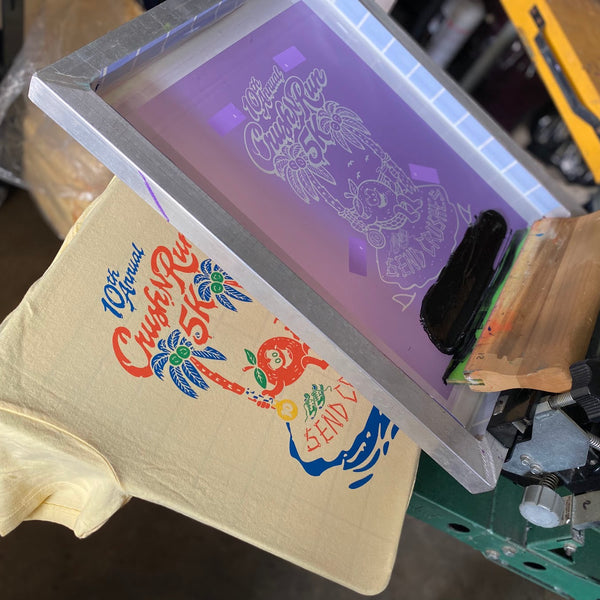 Crush Run screen raised over a printed butter tee on the press at RVA Threads screen printing, Virginia