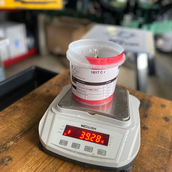 Cup of red ink on a digital scale while mixing a custom ink color at RVA Threads screen printing, Virginia