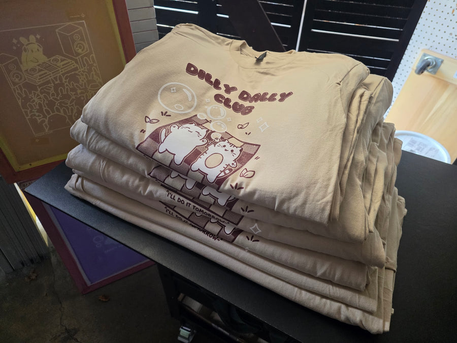 Dilly Dally Club print in maroon and white on Sand Gildan 2000 tees, folded and stacked at RVA Threads screen printing, Virginia