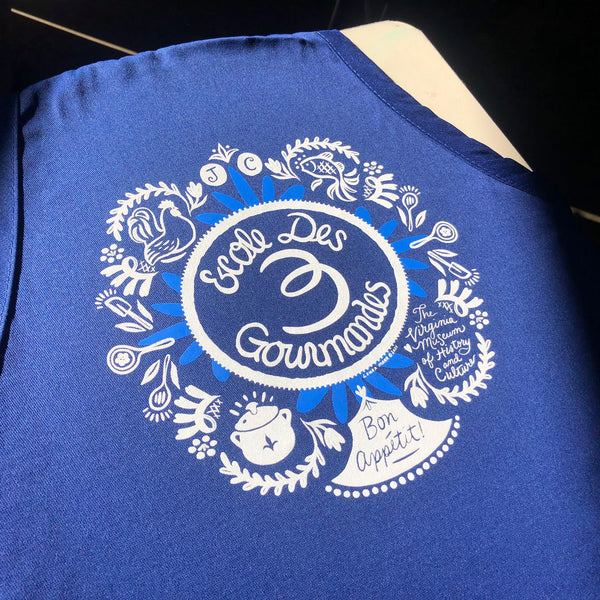 Ecole Des Gourmands Bon Appetit illustrated logo in white ink on a royal blue apron at RVA Threads screen printing, Virginia