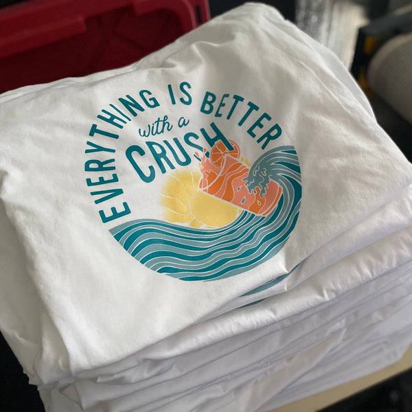 Everything Is Better With a Crush shirts in teal, orange and yellow ink on white, folded and stacked at RVA Threads screen printing, Virginia