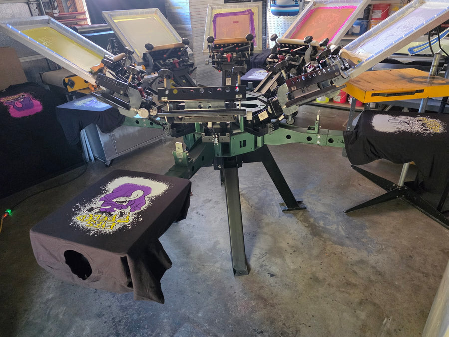 Eyes Peeled tees on the six-color manual press loaded with yellow, pink, purple and white screens at RVA Threads screen printing, Virginia