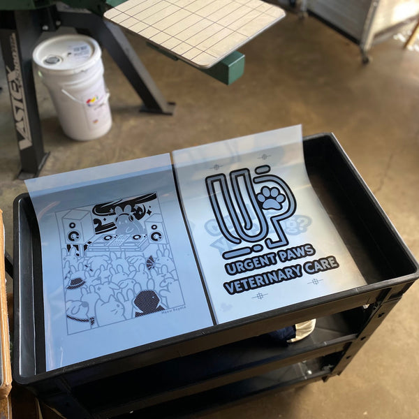 Film positives for Can I Pet Your Dog and Urgent Paws laid out on a cart at RVA Threads screen printing, Virginia