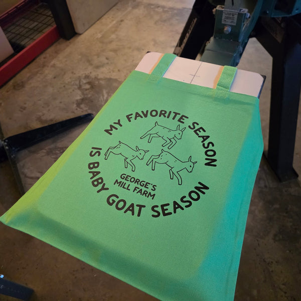 George's Mill Farm My Favorite Season Is Baby Goat Season tote bag printed in black ink on lime, on the press at RVA Threads screen printing, Virginia