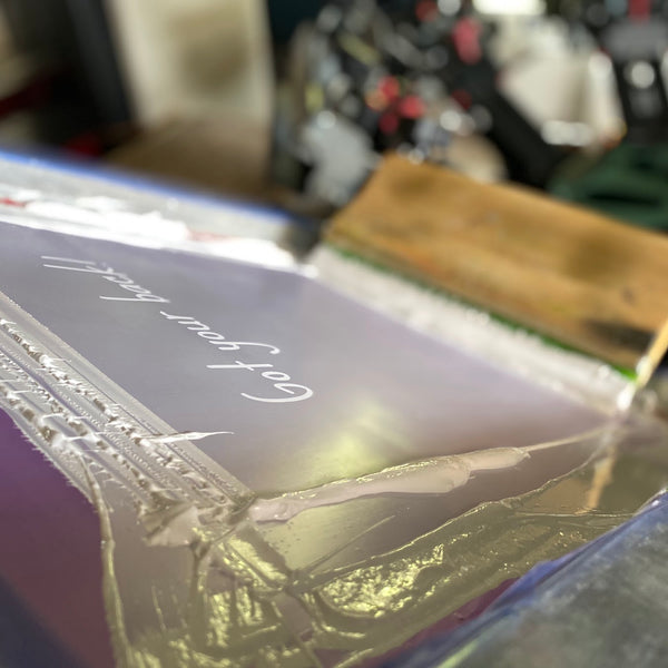 Got Your Back script screen with white ink and the squeegee resting on the press at RVA Threads screen printing, Virginia