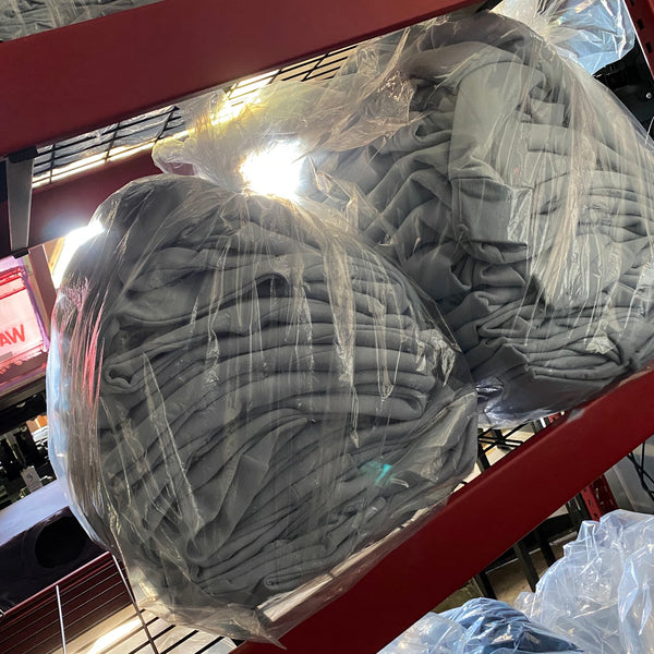 Gray tees bagged in clear plastic and stacked on the red wire shelf, ready for pickup at RVA Threads screen printing, Virginia