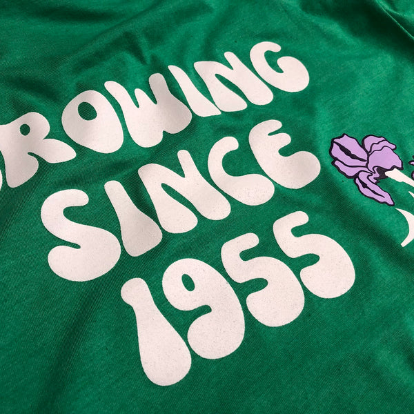 Growing Since 1955 lettering in white ink with an iris on a green tee at RVA Threads screen printing, Virginia