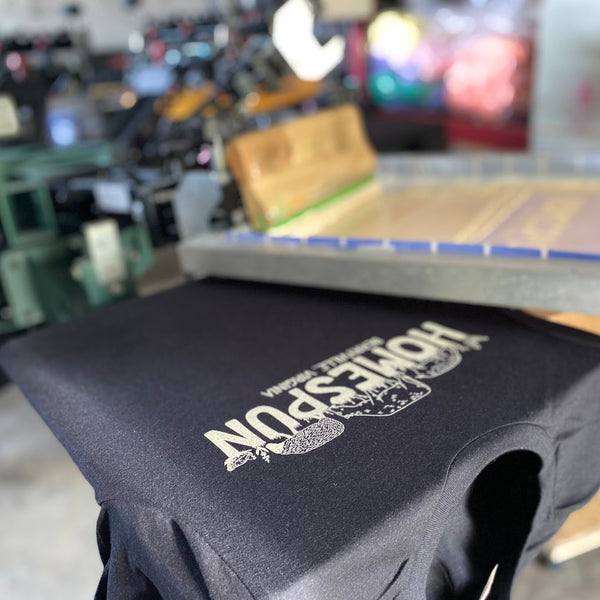 Homespun design in white ink on a black tee on the press pallet at RVA Threads screen printing, Virginia