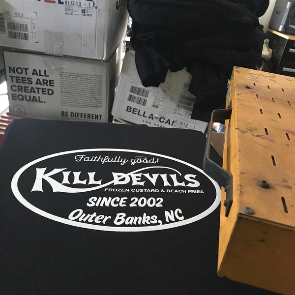 Kill Devils Since 2002 Outer Banks, NC logo in white ink on a black tee on the press at RVA Threads screen printing, Virginia