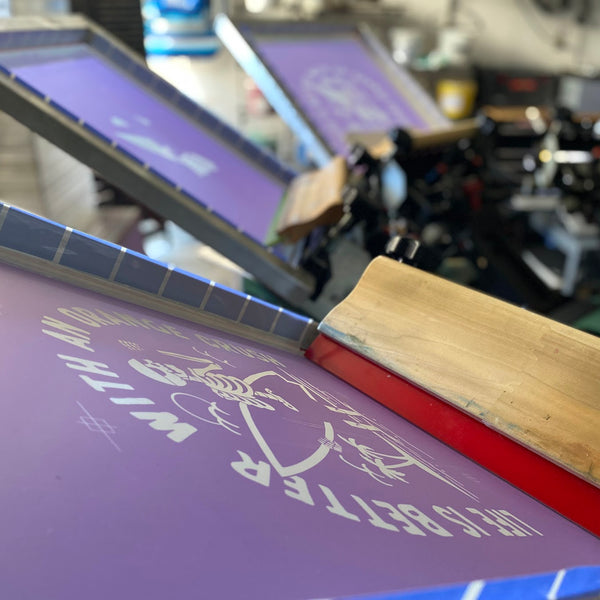 Life Is Better With An Orange Crush screen with white ink and the squeegee on the press at RVA Threads screen printing, Virginia