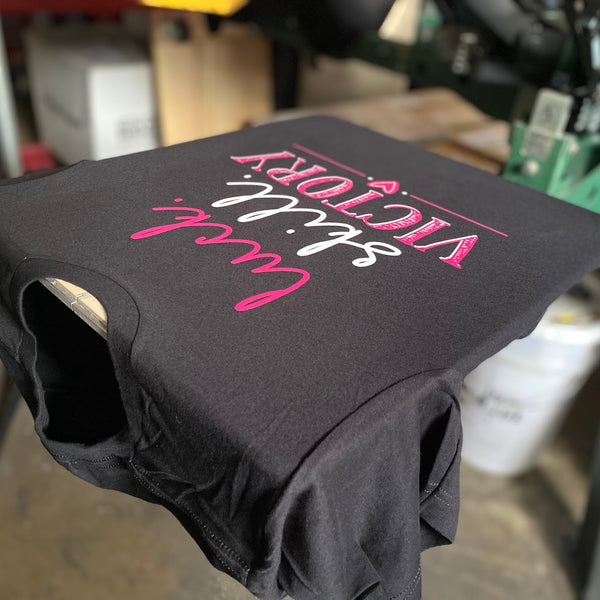 Luck Skill Victory tee in pink and white ink on black Bella+Canvas 3001, laid on the press pallet at RVA Threads screen printing, Virginia