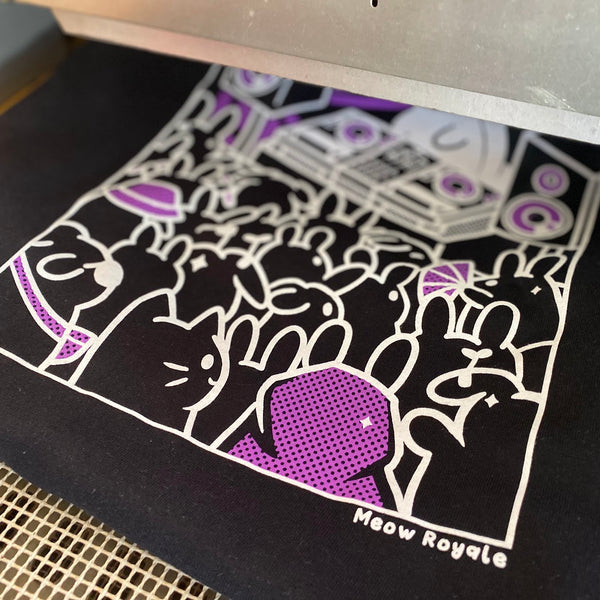 Meow Royale DJ crowd design in purple and white ink on a black tee on the press pallet at RVA Threads screen printing, Virginia