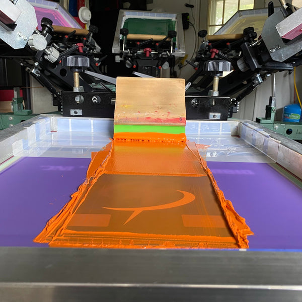 Orange ink screen with the squeegee for the Dibble Electrical lightning logo at RVA Threads screen printing, Virginia