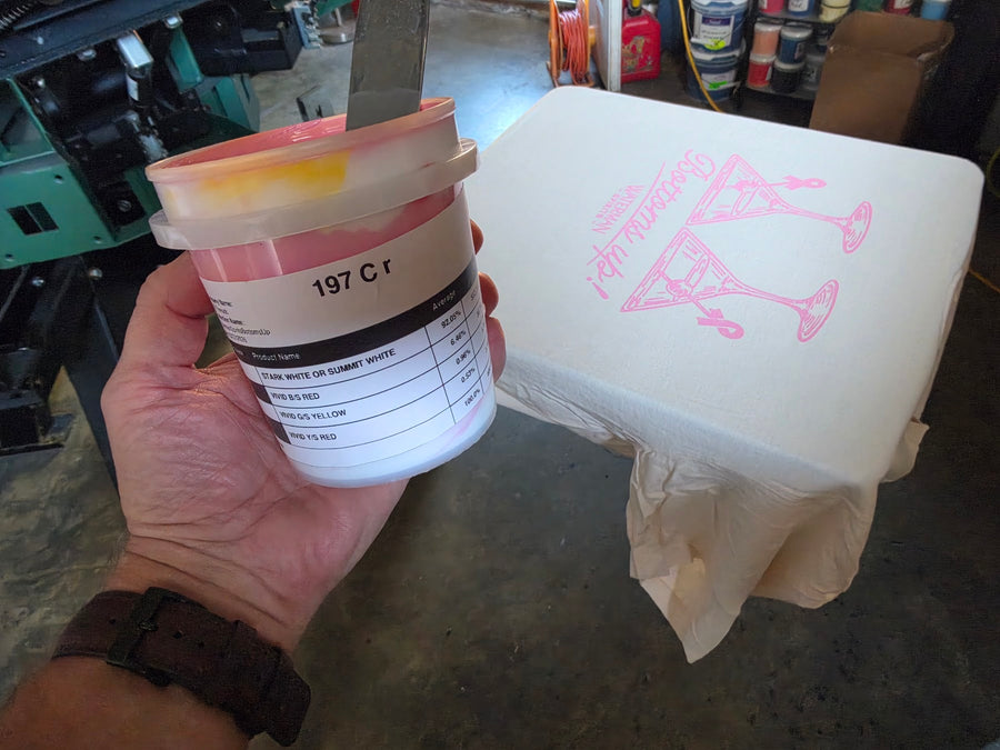 Pantone 197 C pink ink mixed for Waterman Spirits Bottoms Up, held next to the print on an Ivory tee at RVA Threads screen printing, Virginia